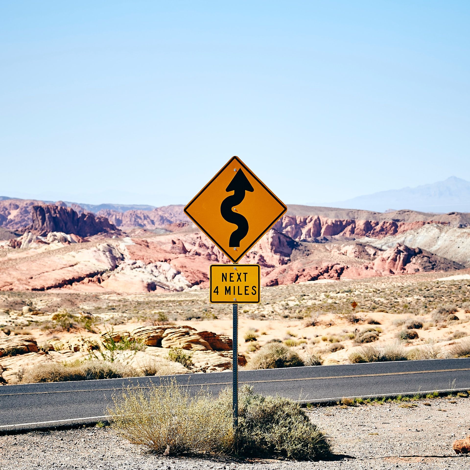 Sign on desert road that shows curves for the next four miles