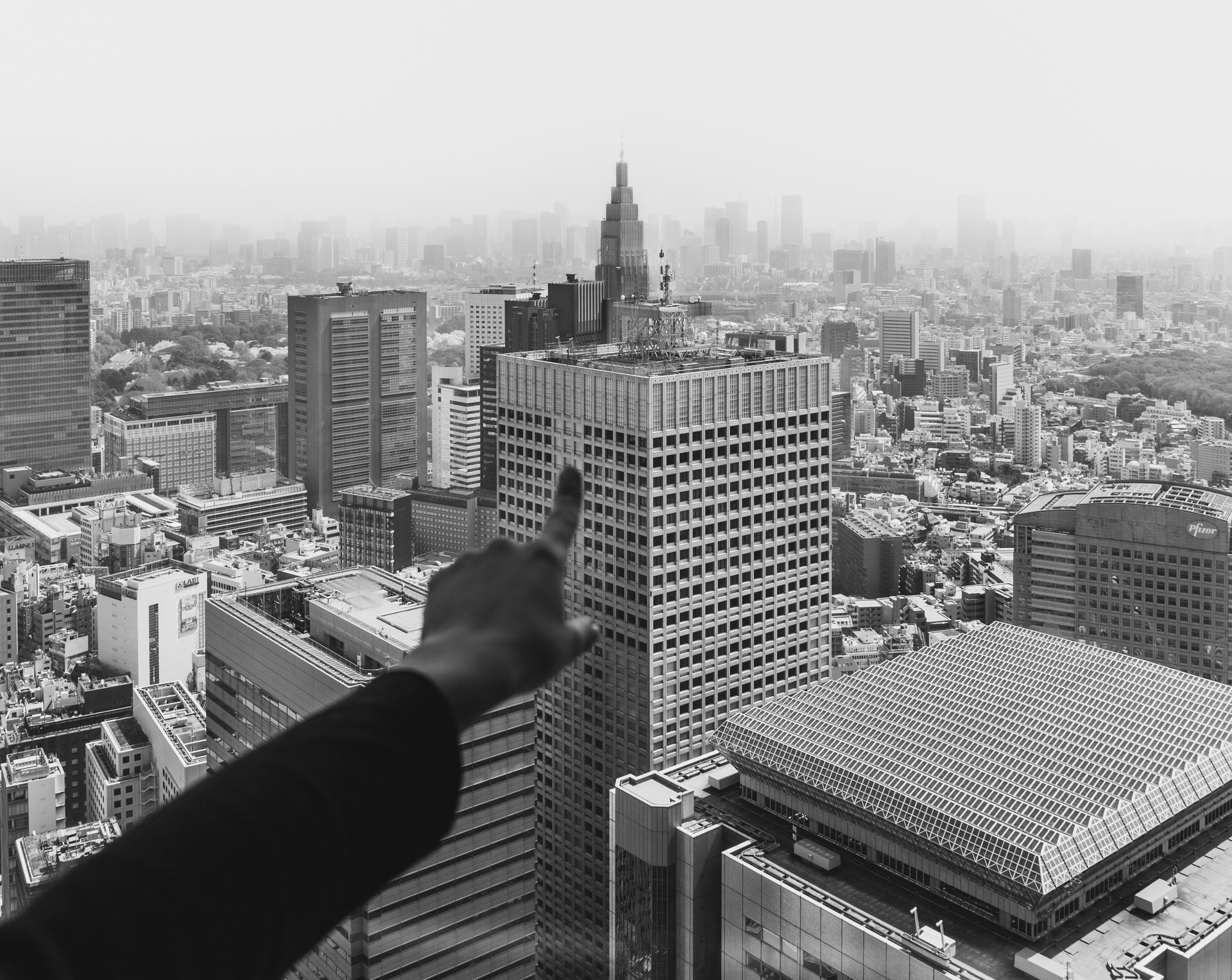 Finger pointing at a skyscraper in a large city