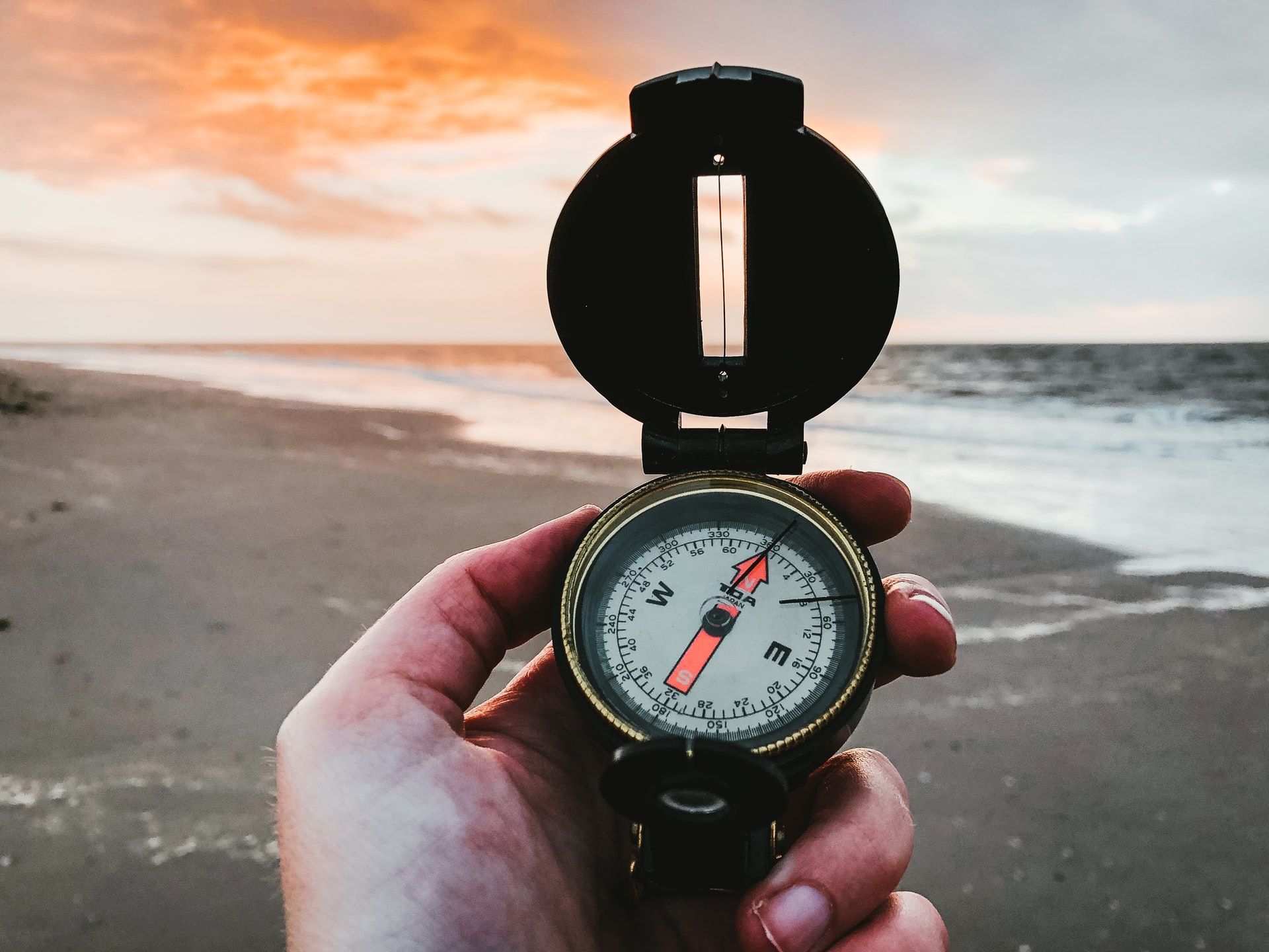 Person holding a compass at the beach